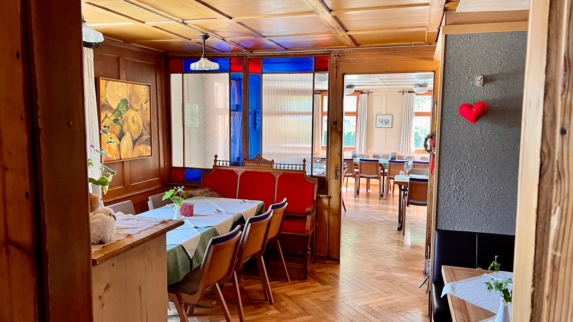 Blick durch die Stuben des Gasthaus Adler mit getäfelter Wand, Buntglasfenster und roter Sitzbank